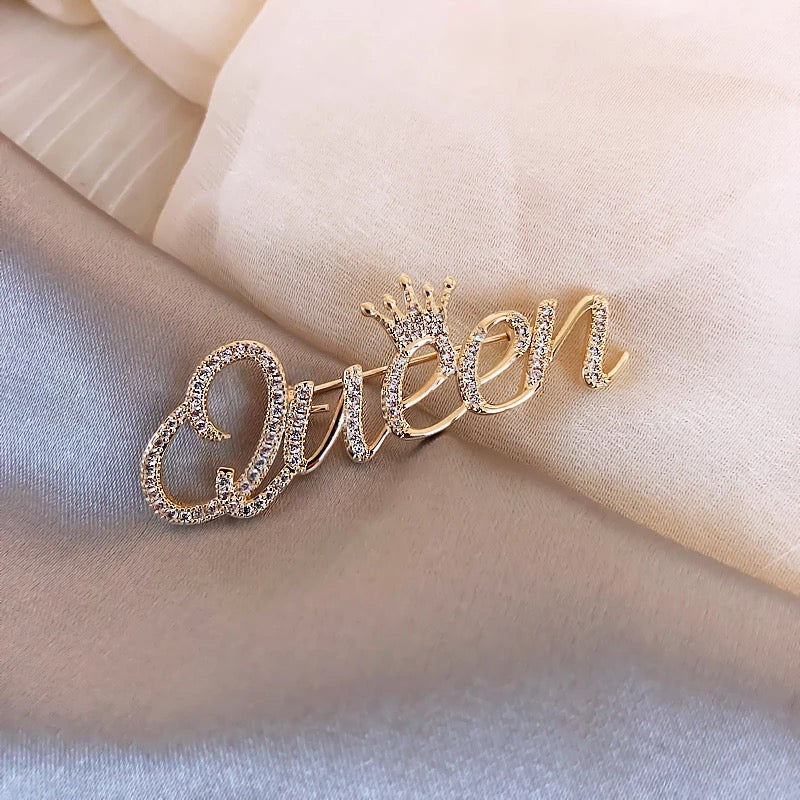 Goldinschrift „Queen“ mit einer Krone – Brosche mit Zirkonia