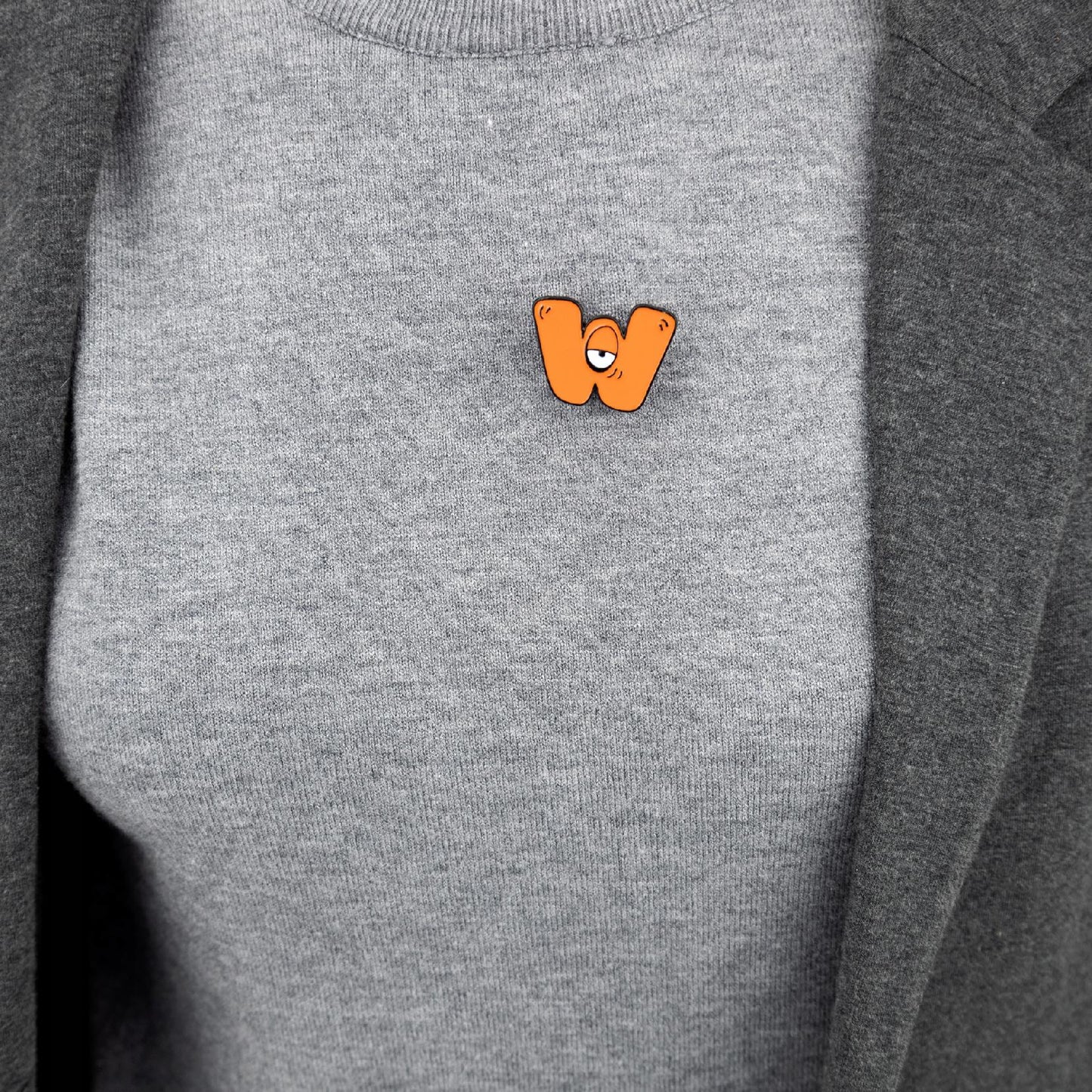 Buchstabe W mit Auge - orangefarbene Anstecknadel