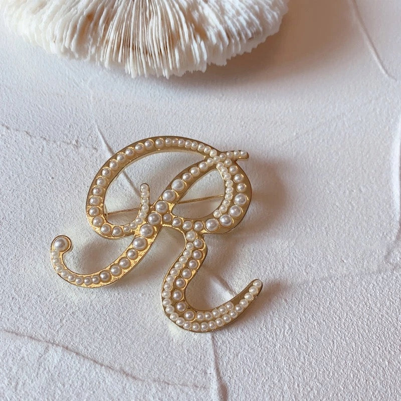 Goldene Brosche mit dem Buchstaben R und Perlen