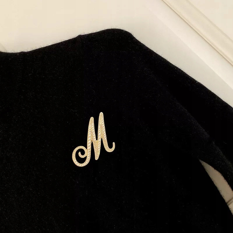 Goldene Brosche mit dem Buchstaben M und Perlen