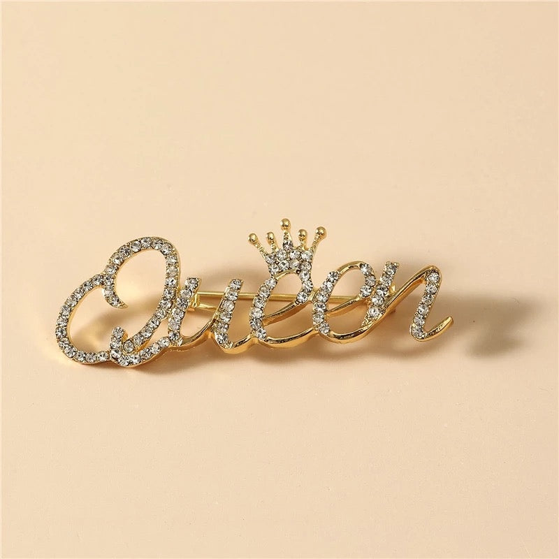 Goldinschrift „Queen“ mit einer Krone – Brosche mit Zirkonia