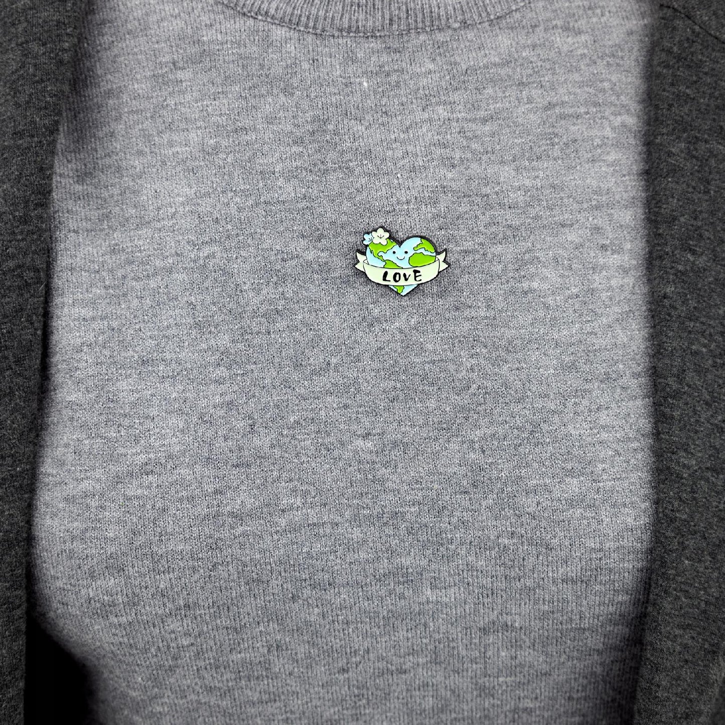 Umweltfreundlicher Pin mit einem Herz in Form des Planeten Erde und der Aufschrift „Love“