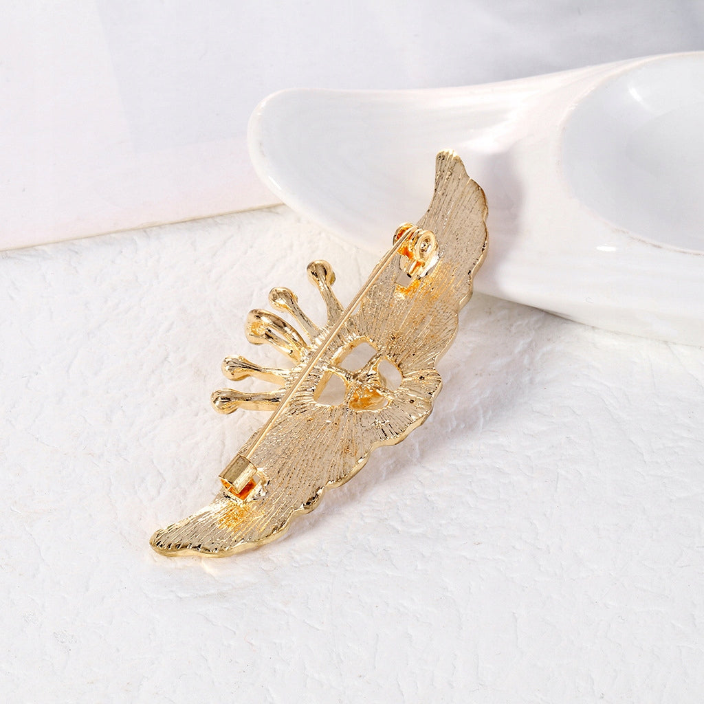 Flügel mit einer Krone - goldene Brosche mit Zirkonen und einer Perle