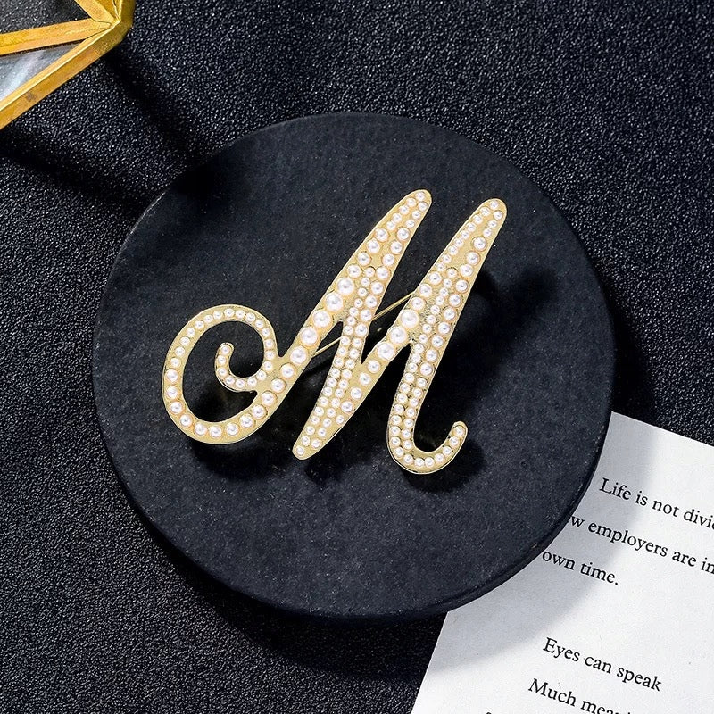 Goldene Brosche mit dem Buchstaben M und Perlen