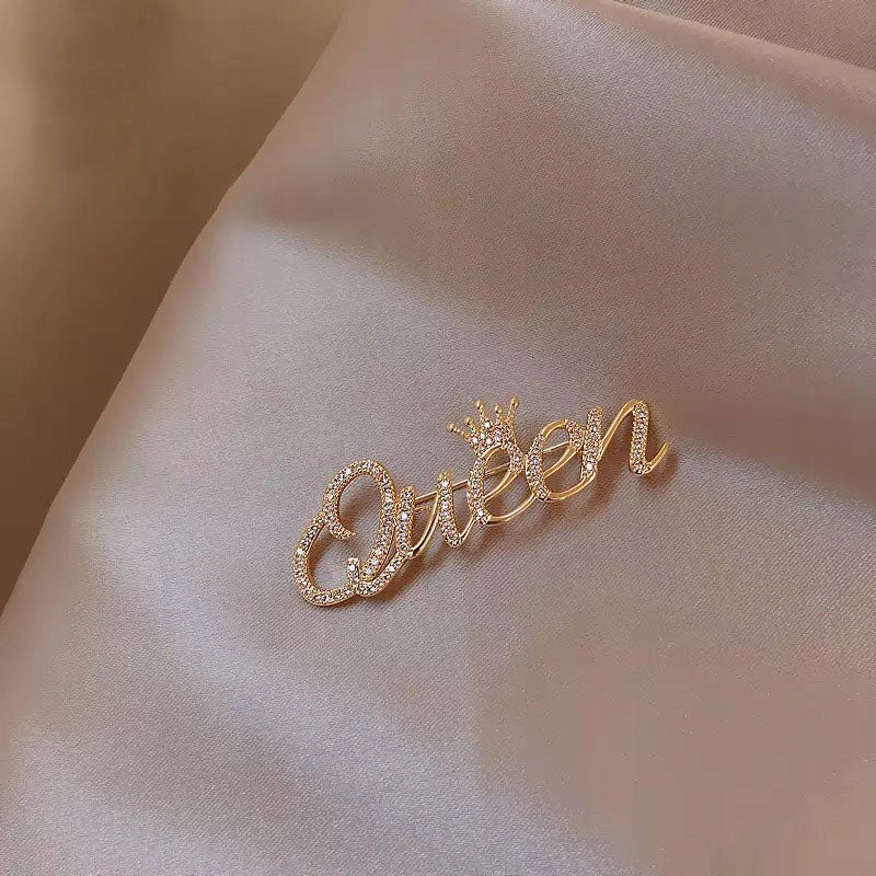 Goldinschrift „Queen“ mit einer Krone – Brosche mit Zirkonia