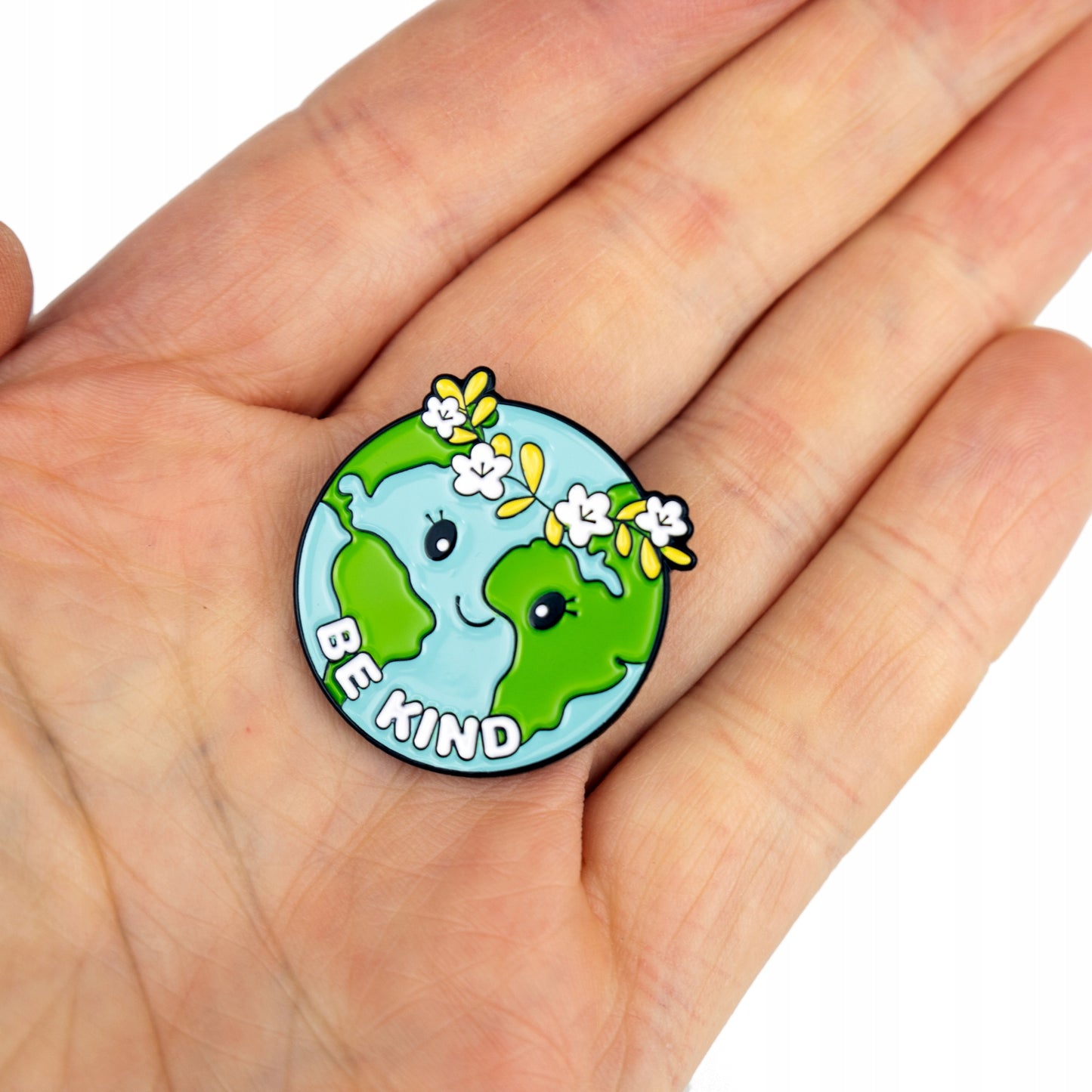 Ökologische Anstecknadel in Form des Planeten Erde mit einem Kranz und dem Slogan „Be Kind“