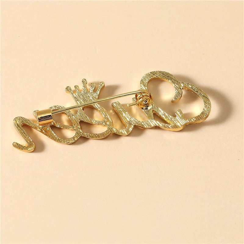 Goldinschrift „Queen“ mit einer Krone – Brosche mit Zirkonia