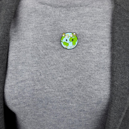 Ökologische Anstecknadel in Form des Planeten Erde mit einem Kranz und dem Slogan „Be Kind“